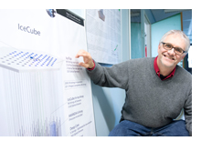 Professor Lutz Köpke uses a model to explain the IceCube detector and its structure: Eighty six 60 centimert-wide channels were melted into the snow surface where sensors were placed at depths of 1,450-2,450 meters and then frozen in place. The blue cone represents Cherenkov light radiation along the trail of a particle. The size of the colored cone indicates how much light the sensor has registered, the rainbow colors indicate the time (earlier arrival: red, later arrival: blue). (photo: Peter Pulkowski)